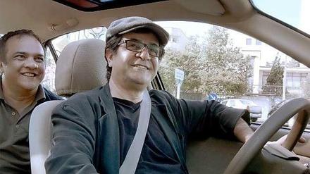 Er kann immer noch lächeln: Jafar Panahi (r.) hat bereits viele Rückschläge erlebt. Doch er übt seinen Beruf unverdrossen weiter aus - wie hier in seinem Gewinnerfilm "Taxi".