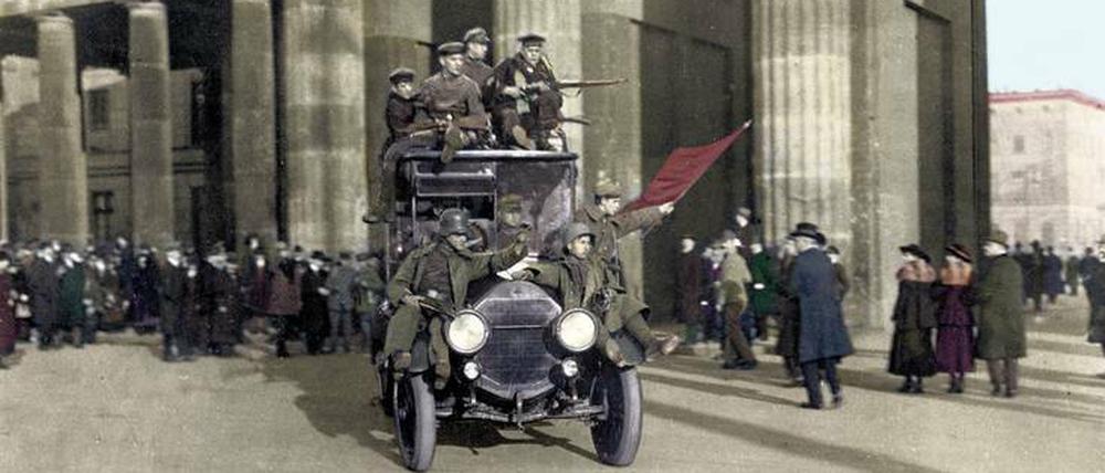 Ganz ohne Bahnsteigkarte. Revolutionäre Truppen bahnen sich am 11. November 1918 vor dem Brandenburger Tor ihren Weg durch überraschte, doch nach guter Sitte ausgehfein gekleidete Bürger (zeitgenössisch handkolorierte Aufnahme).