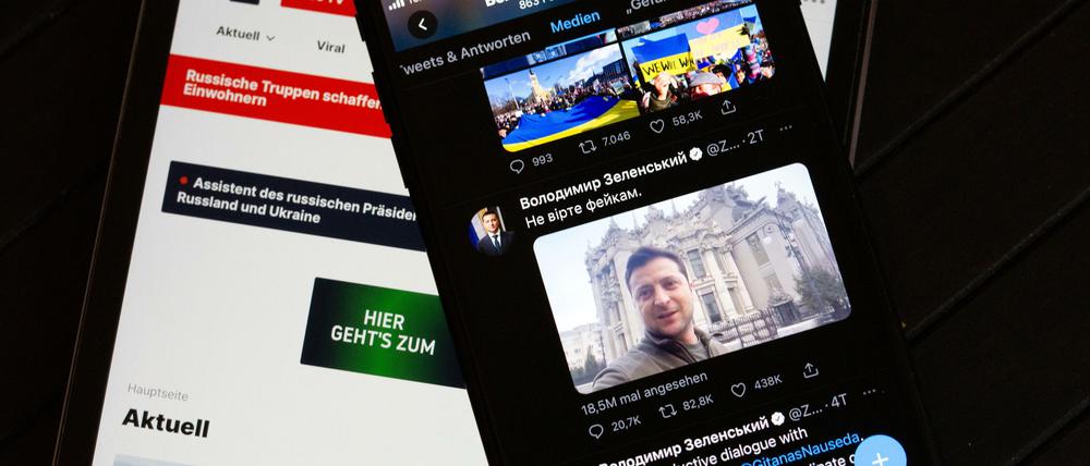 Auf dem Bildschirm eines Tablets (l.) ist die Website des russischen Fernsehsenders RT zu sehen. Rechts ist auf dem Bildschirm eines Smartphones der offizielle Twitter-Account des ukrainischen Präsidenten Selenskyj zu sehen.