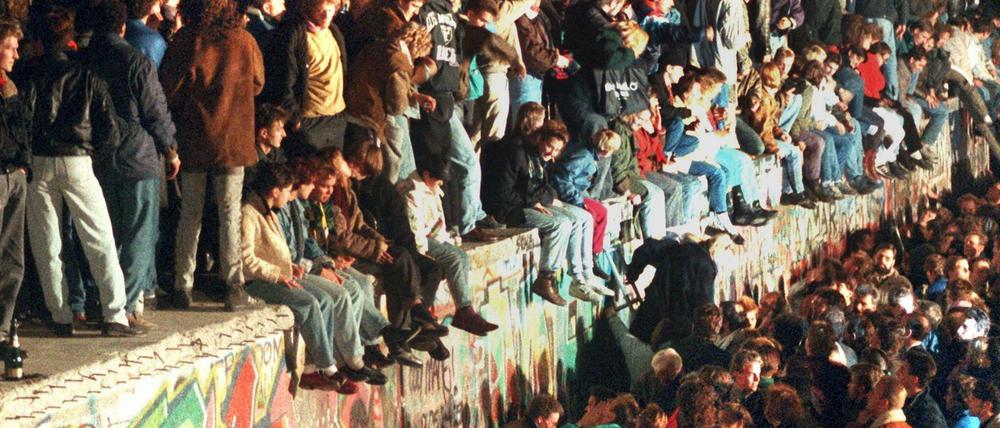 Menschen sitzen auf der Berliner Mauer - allerdings am 11.11.1989.