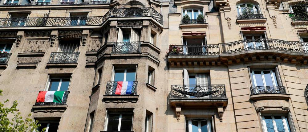 EU in Quarantäne. Die italienische und die französische Flagge an einer Häuserfront in Paris