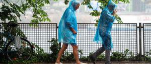 06.06.2019, Berlin: Eine Frau und ein Mann laufen in blauen Regencapes durch den Regen. Foto: Lisa Ducret/dpa +++ dpa-Bildfunk +++