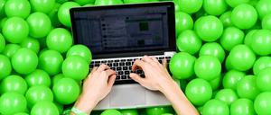 Eine Teilnehmerin der Internetkonferenz re:publica benutzt ihr Laptop in einem Bällebad mit grünen Bällen. 