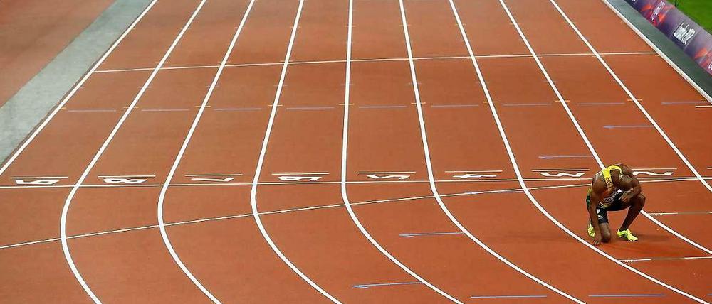 Das Bild zeigt den Sprinter Asafa Powell. Er hockt allein in der Bahn und bereitet sich auf den Start eines Rennens bei den Olympischen Spielen 2012 vor.