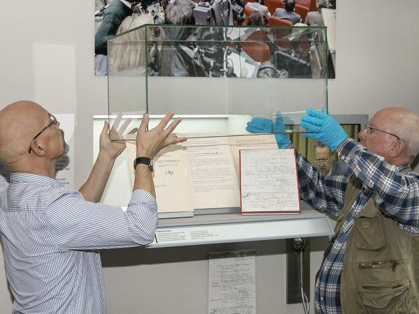 Volker Thiel, leitender Registrar, und Restaurator Norbert Schmitt öffnen die Vitrine mit Schabowskis Zettel im Haus der Geschichte in Bonn.