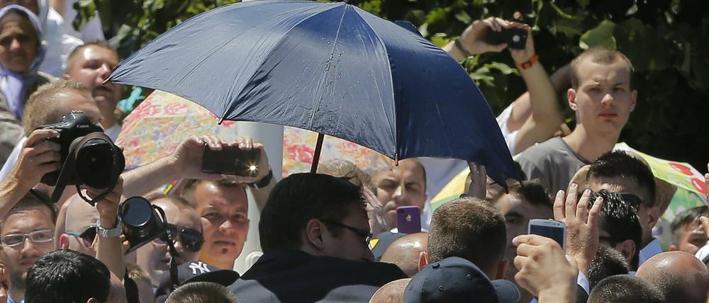 Leibwächter schützen den von einer Menschenmenge bedrängten serbischen Ministerpräsidenten Aleksandar Vucic.
