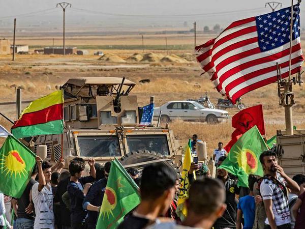 Im Schutz von US-Soldaten demonstrieren kurdische Linke in Syrien gegen einen türkischen Einmarsch.