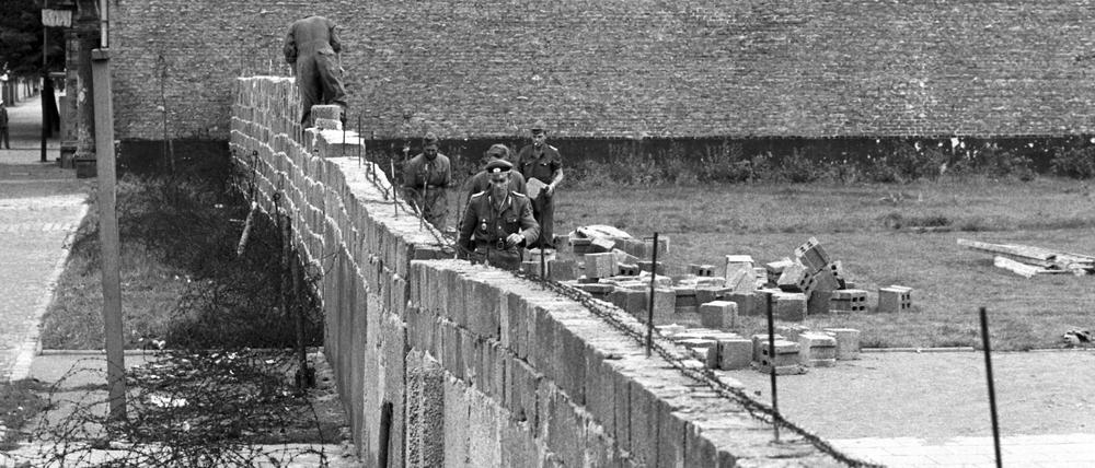 Volkspolizisten und Arbeiter der DDR errichten die Mauer im Norden Berlins an der Grenze zum westberliner Bezirk Reinickendorf.