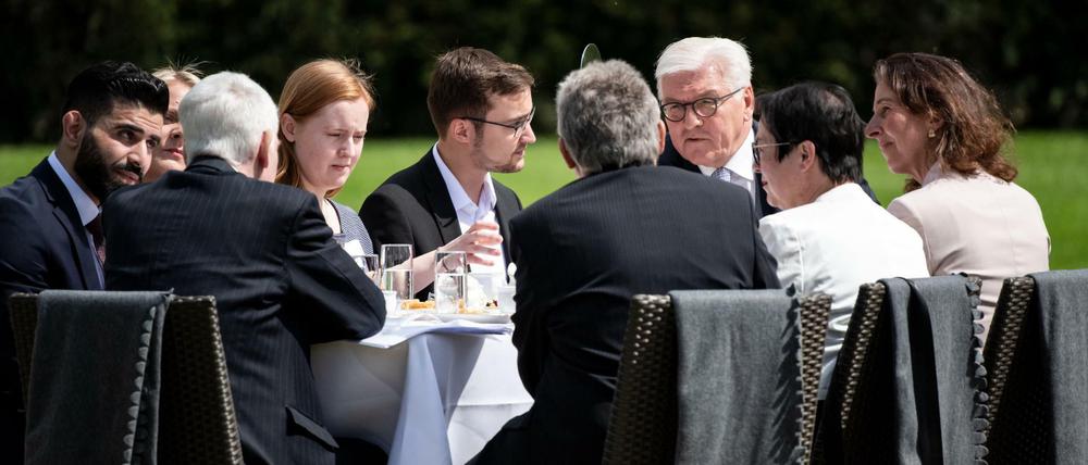 Bundespräsident Frank-Walter Steinmeier (3.v.r) unterhält sich bei der Geburtstagskaffeetafel zum 70. Jahrestag des Grundgesetzes im Park von Schloss Bellevue mit Gästen.