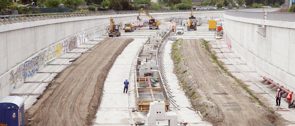 Bauarbeiter bringen auf der Baustelle der Erweiterung der A100 im Bezirk Neukölln den Untergrund für die Fahrbahnen auf. Die A100 wird in Richtung Friedrichshain ausgebaut, um den Berliner Osten besser an die Stadtautobahn anzubinden. 