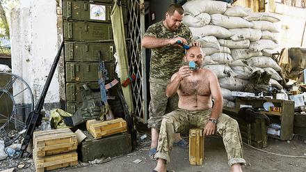 Ein ukrainischer Soldat lässt sich von einem Kameraden den Schädel rasieren.