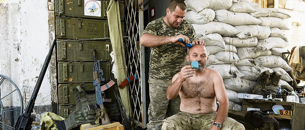 Ein ukrainischer Soldat lässt sich von einem Kameraden den Schädel rasieren.