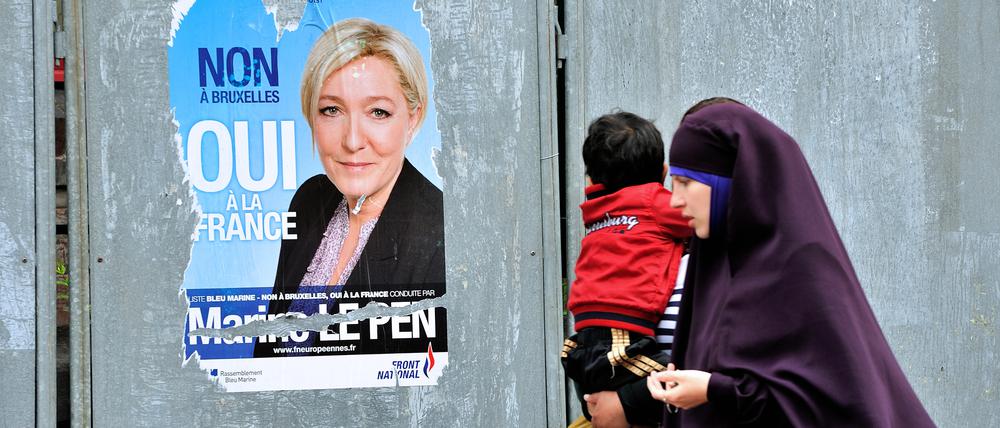 Passantinnen mit einem Jungen gehen im nordfranzösischen Valenciennes an einem Plakat der Front-National-Chefin Marine Le Pen vorbei.