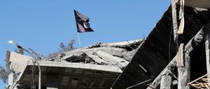 Eine Flagge von Kämpfern des Islamischen Staates ist auf einem zerstörten Haus im syrischen Raqqa zu sehen.