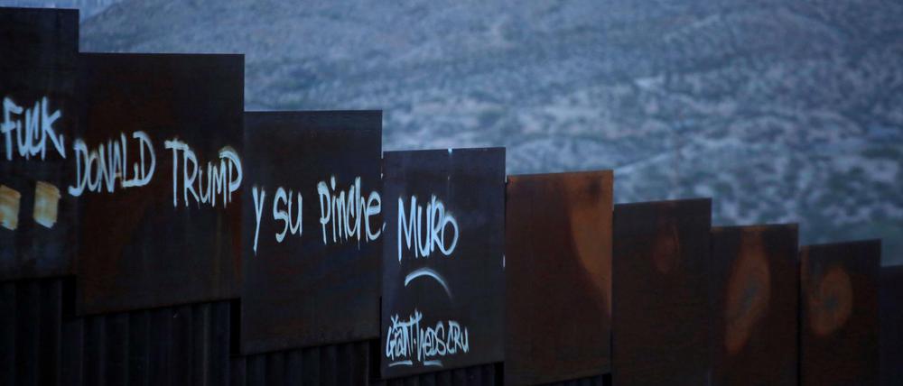 Ein Grenzzaun zwischen der USA und Mexiko mit einer Schmähung des US-Präsidenten