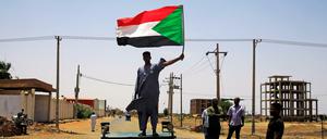 Ein Demonstrant mit einer sudanesischen Flagge an einer Straßenbarrikade