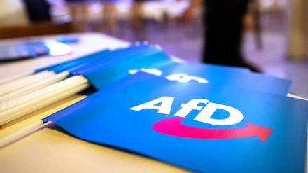 Fähnchen mit dem Logo der AfD liegen beim Landesparteitag der AfD Bayern auf einem Tisch. 