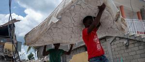 Erdbeben auf Haiti: Männer tragen eine Matratze aus einem zerstörten Hotel.