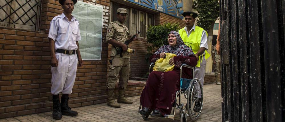 Ägypten wählt. Ein Polizist hilft einer Rollstuhlfahrerin am Sonntag ins Wahllokal in Kairo. 