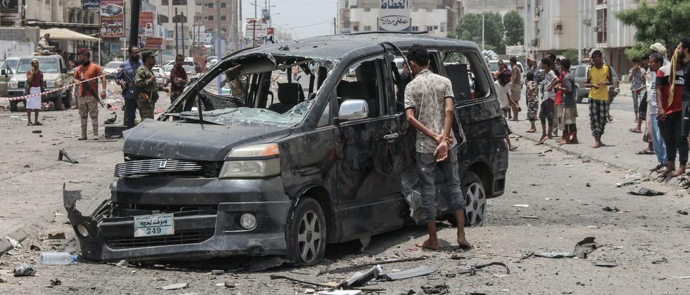 Ein Junge schaut sich ein schwer beschädigtes Auto nach einem Autobombenanschlag neben einer dadurch zerstörten Polizeistation an. 