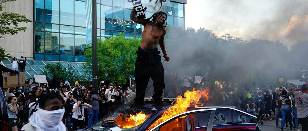 Ein Demonstrant steht auf einem brennenden Polizeiauto in Atlanta. =
