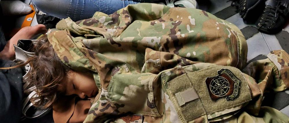 Ein Kind schläft am Flughafen Kabul unter einer US-Militärjacke.