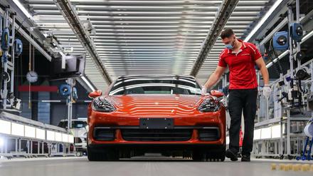 Ein Mitarbeiter von Porsche führt im Werk in Leipzig die finale Qualitätskontrolle an einem Panamera durch.