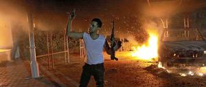 Ein Mann steht mit seiner Waffe vor dem brennenden US-Konsulat in Bengasi.