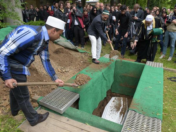 Bestatter schaufeln am 19.06.2015 Erde auf Sarg mit den sterblichen Überresten eines 60-jährigen Flüchtlings auf dem Friedhof Alter Zwölf-Apostel-Kirchhof in Berlin. Die Beerdigung ist eine Aktion des "Zentrum für Politische Schönheit" die damit gegen die EU-Flüchtlingspolitik protestiert.