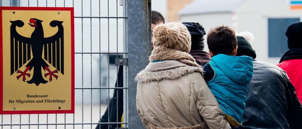 Flüchtlinge stehen 2015 neben einem Schild vom "Bundesamt für Migration und Flüchtlinge" an der Landesaufnahmebehörde Niedersachsen in Braunschweig.