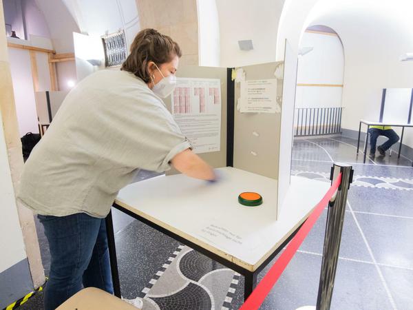 Ein städtische Mitarbeiterin desinfiziert eine Wahlkabine in Hannover.