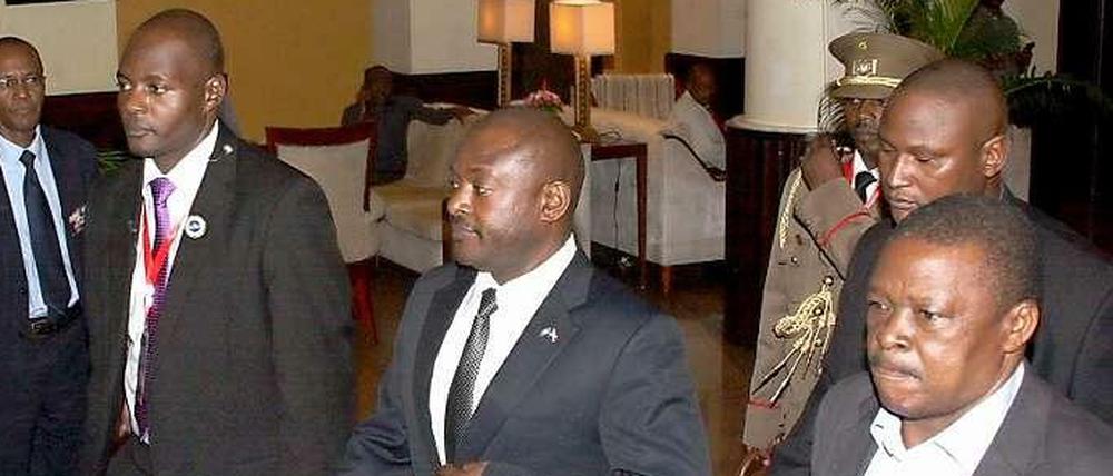Burundis Präsident Pierre Nkurunziza wird von seinen Sicherheitsleuten aus einem Hotel in der tansanischen Hafenstadt Daressalam geführt. Er machte sich dann auf dem Landweg auf zurück in sein Heimatland. 