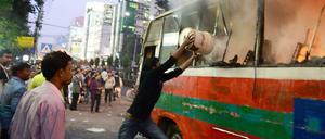 Gewalt in Bangladesch. Freiwillige löschen einen Bus, der vermutlich von Regierungsgegnern in Brand gesteckt worden war.