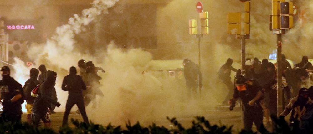 Katalanische Demonstranten werfen einen Tränengas-Behälter zurück auf die Polizei.