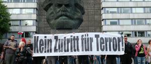 Rechte Demonstranten halten am Montag vor dem Karl-Marx-Monument in Chemnitz ein Plakat hoch. 
