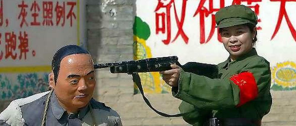 Posieren für die Kulturrevolution: Eine Touristin in Soldatenuniform spielt in einem chinesischen Themenpark mit einer Sträflingsstatue eine Exekution nach. 