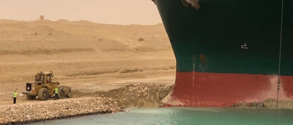 Ein Bagger versucht, das vordere Ende des von Evergreen Marine betriebenen Containerschiffs Ever Given zu befreien, nachdem es im südlichen Ende des Suezkanals auf Grund gelaufen ist und den Schiffsverkehr in beide Richtungen blockierte.  