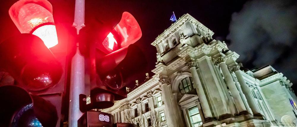 Eine rote Ampel leuchtet vor dem Reichstagsgebäude bei Nacht.