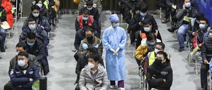 Eine Medizinerin geht zwischen Menschen entlang, die in Peking gerade eine Impfdosis mit einem Corona-Impfstoff erhalten haben.