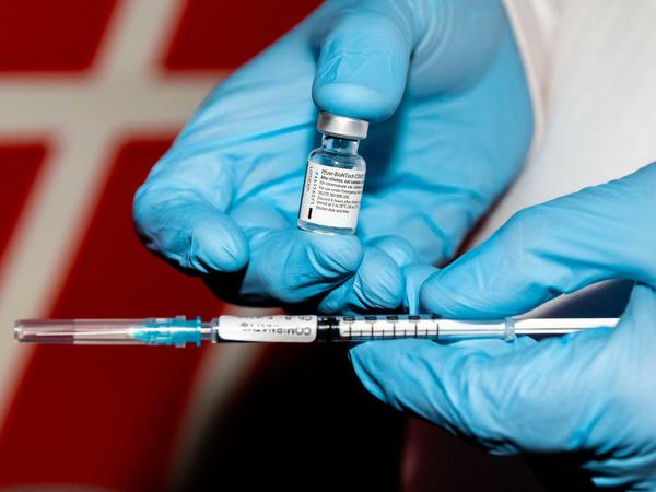 Ein Feuerwehrarzt hält in Hannover eine Ampulle mit Corona-Impfstoff und eine Spritze