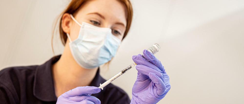 Eine Helferin zieht in der Impfkabine eines Impfzentrums eine Spritze mit Corona-Impfstoff auf. 