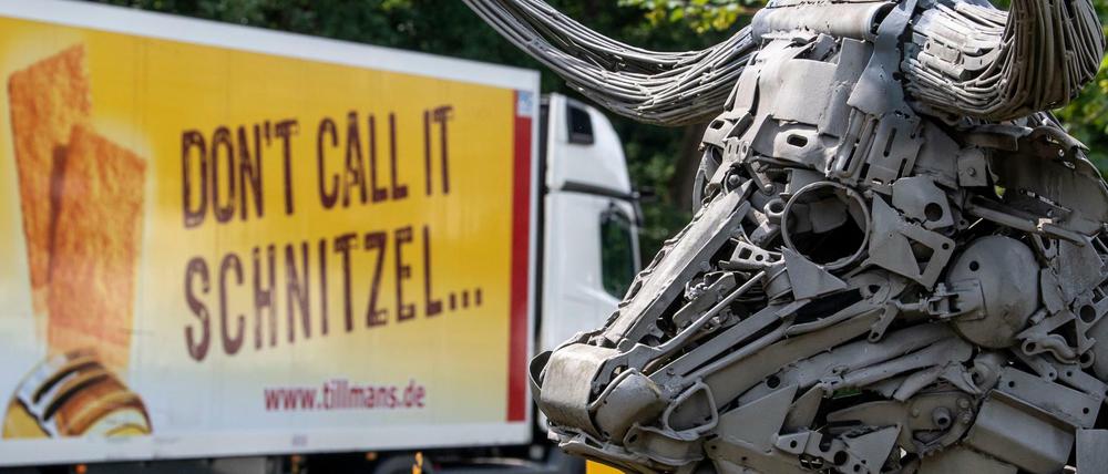 Ein LKW der Tönnies-Tochterfirma Tillmanns mit der Aufschrift "Don·t call it Schnitze" fährt an einer Plastik vorbei, die einen Bullen darstellt. 