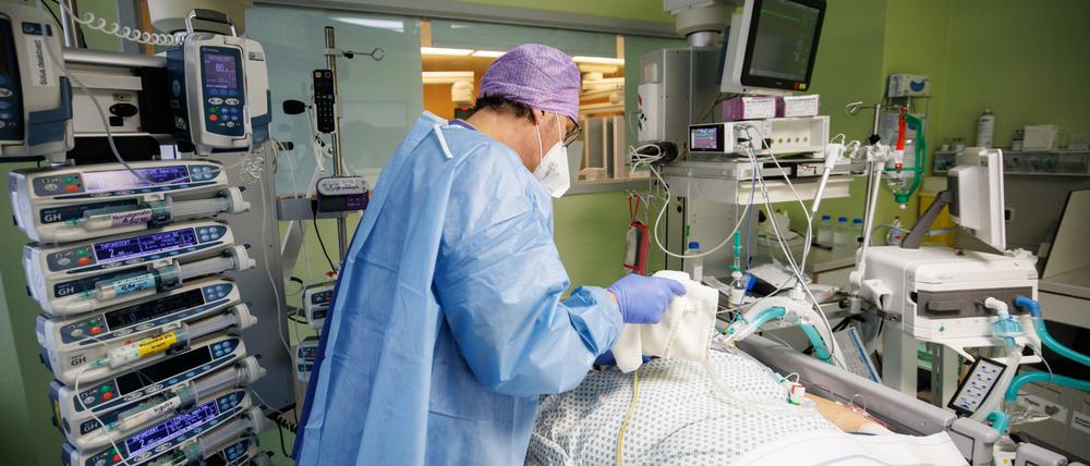 Ein Arzt der Asklepios Klinik in Bayern arbeitet in Schutzkleidung am Bett eines über einen Luftröhrenschnitt beatmeten Corona-Patienten.