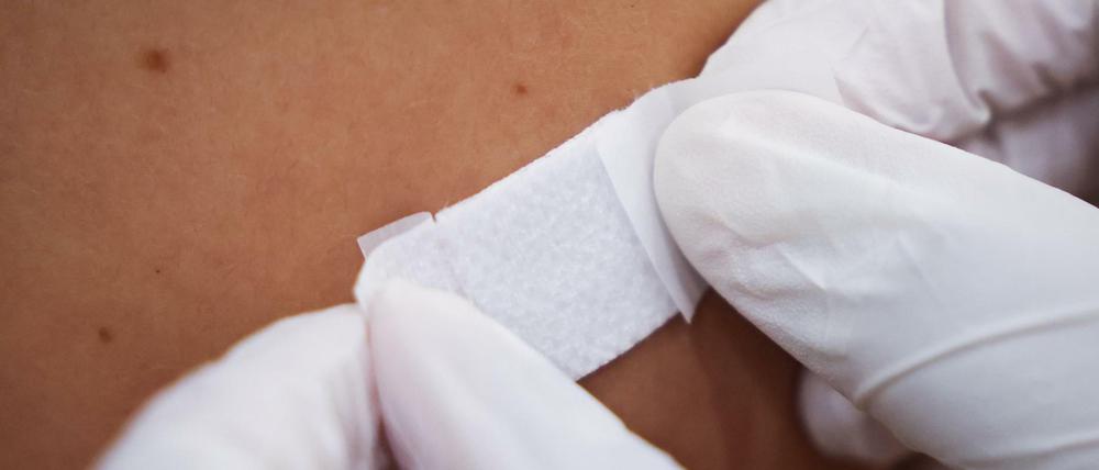 Eine Ärztin klebt nach einer Corona-Impfung ein Pflaster auf den Arm eines Impflings im Hamburger Impfzentrum. 
