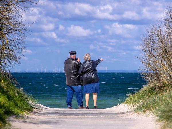 Ein Rentnerpaar steht am ansonsten menschenleeren Strand in Mecklenburg-Vorpommern und schaut aufs Meer.