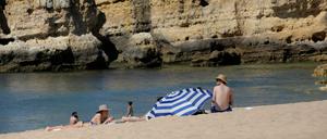Menschen sitzen am Sao-Rafael-Strand in Portugal, Albufeira, in der Sonne.