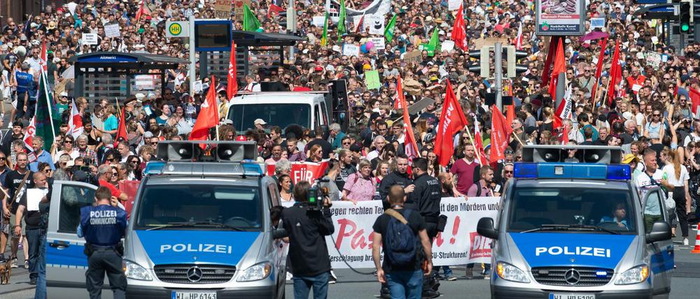 Teilnehmer einer Gegendemonstration gehen mit Plakaten und Flaggen durch Kassel