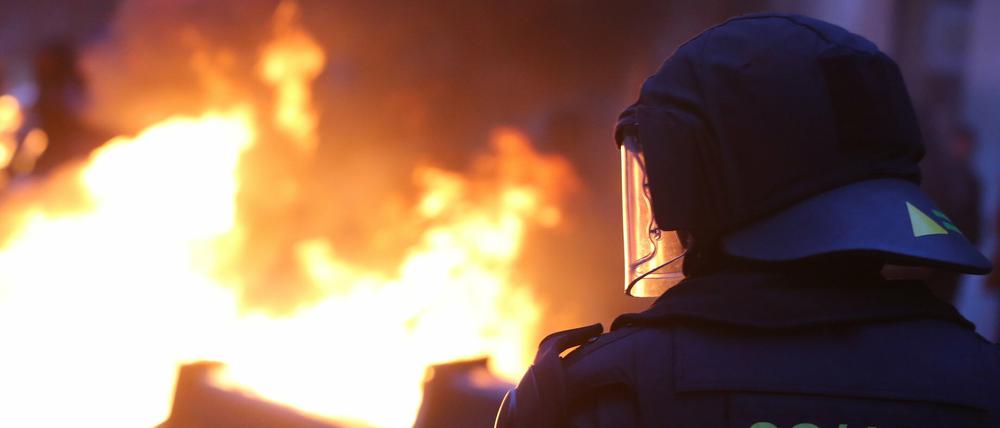 Ein Polizist steht avor einer brennenden Barrikade bei Auseinandersetzungen zwischen linken Gegendemonstranten und der Polizei bei einer Demonstration von Rechtsradikalen.