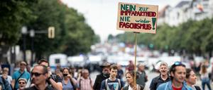 Demonstranten gegen die Corona-Maßnahmen laufen die Bismarckstraße mit einem Schild mit der Aufschrift "Nein zur Impfapartheid nie wieder Faschismus" entlang.