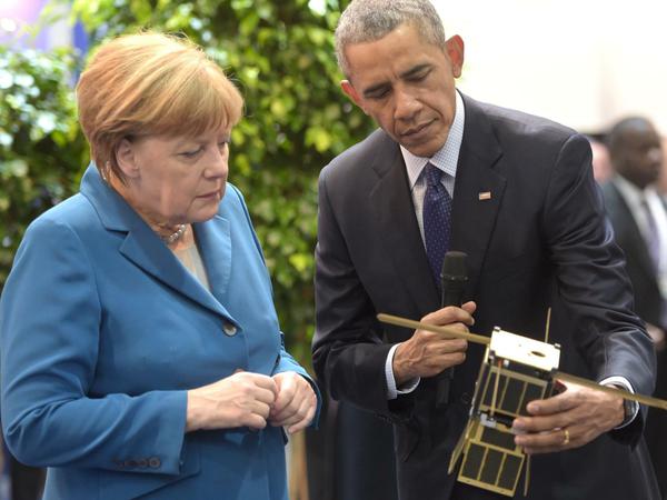 Angela Merkel und Barack Obama schauen sich das Modell eines Satelliten an - am Stand von Kentucky.